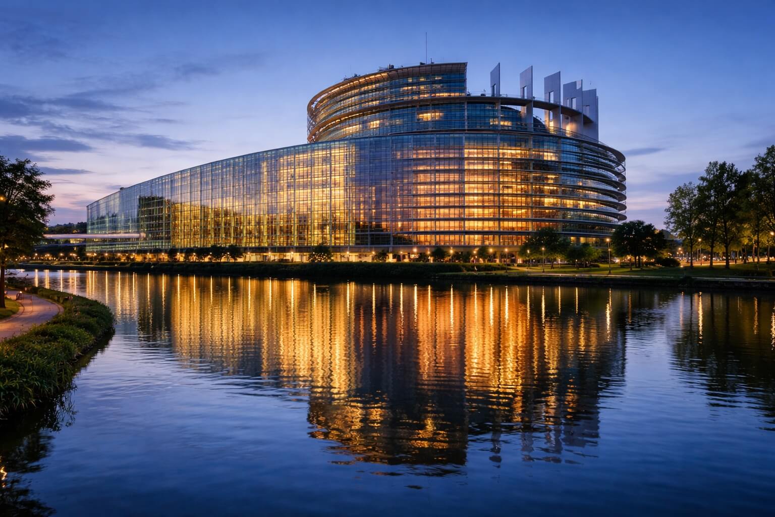 Vue du Parlement européen illuminé en fin de journée, dans une atmosphère contemporaine et solennelle.