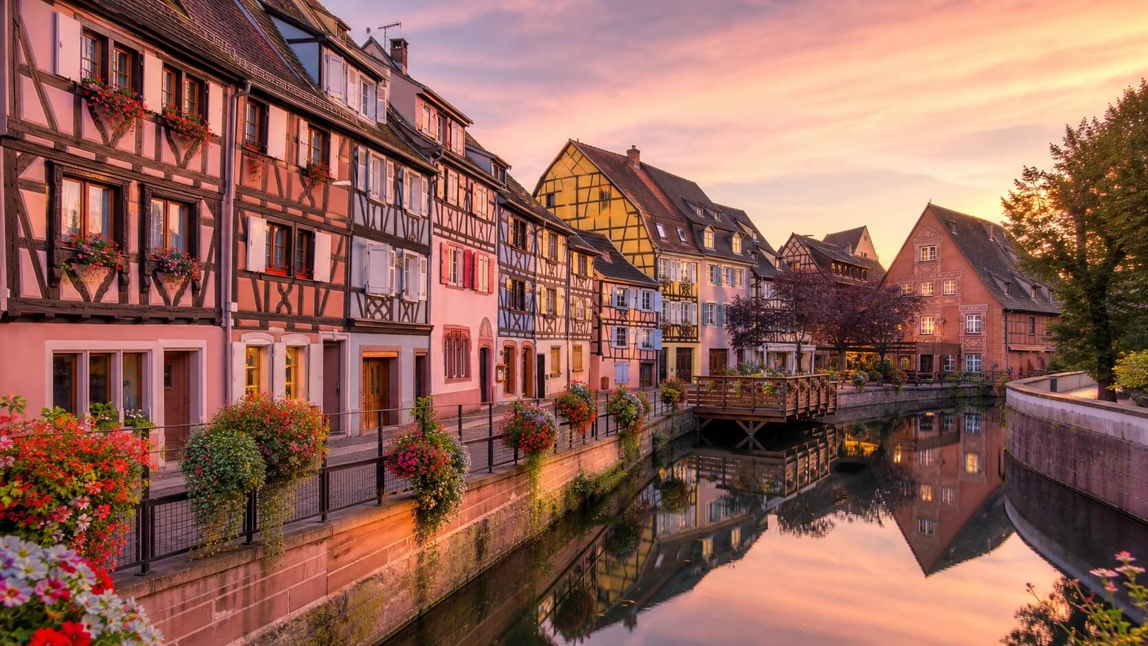 Maisons à colombages colorées de la Petite Venise à Colmar se reflétant dans la rivière au coucher du soleil
