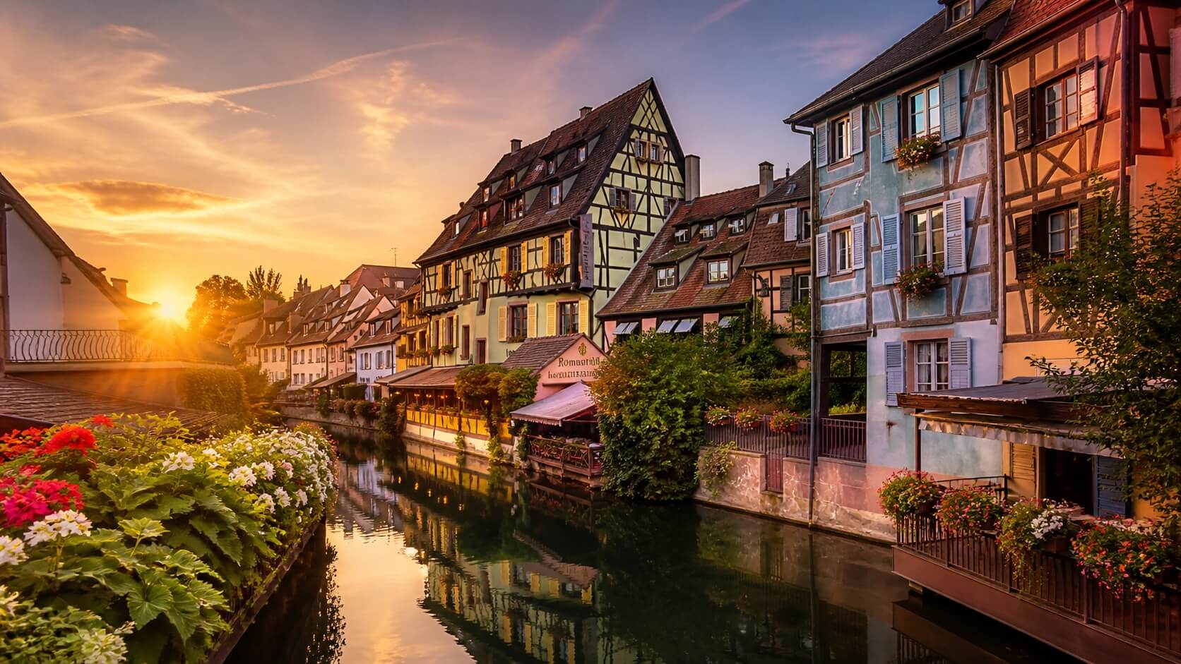 Maisons colorées à colombages dans le quartier de la Petite Venise à Colmar avec canal et reflets au lever du soleil