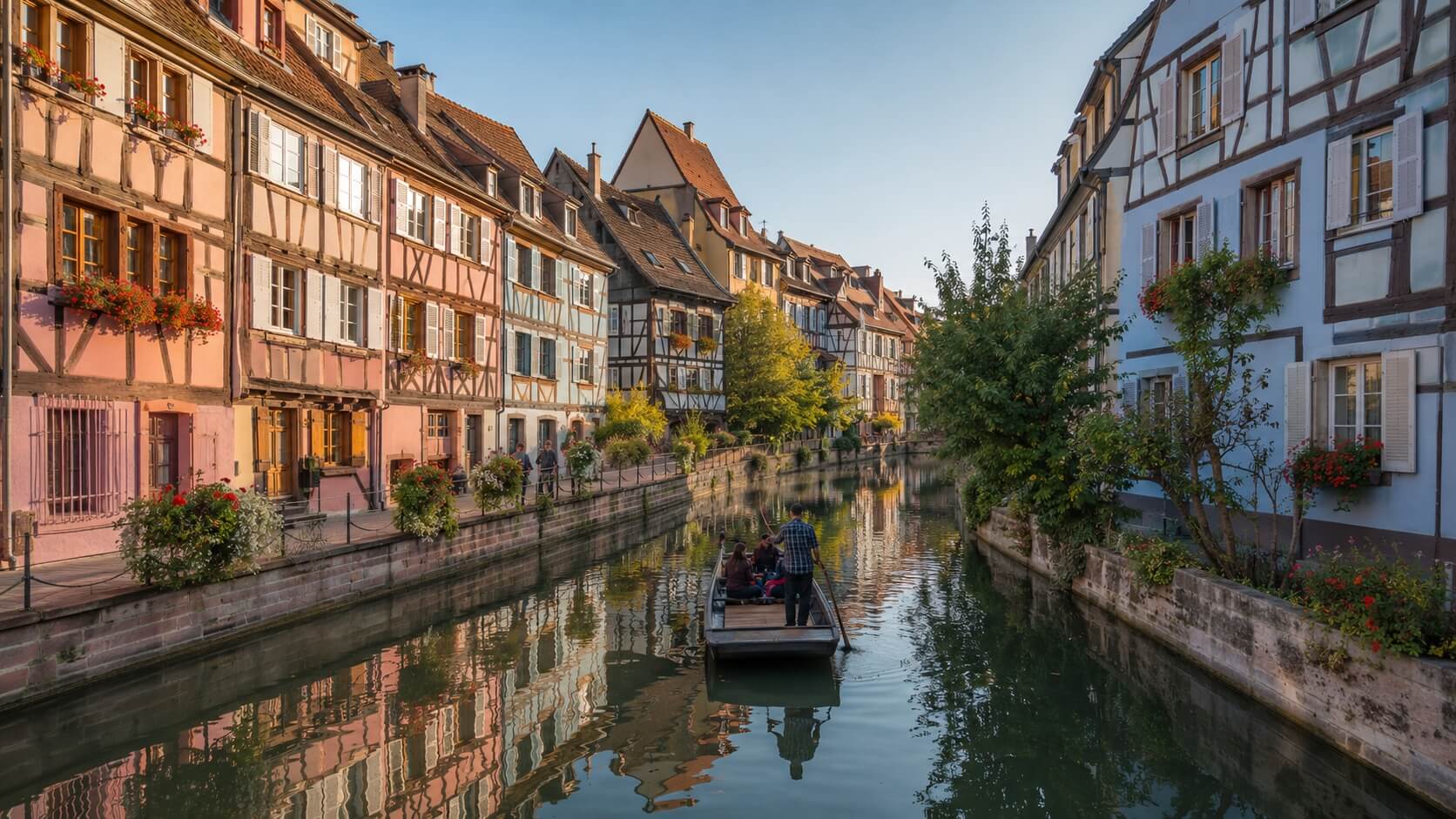 Vue de la Petite Venise à Colmar depuis le pont Saint-Pierre, avec la rivière Lauch, des maisons à colombages colorées et une barque traditionnelle.