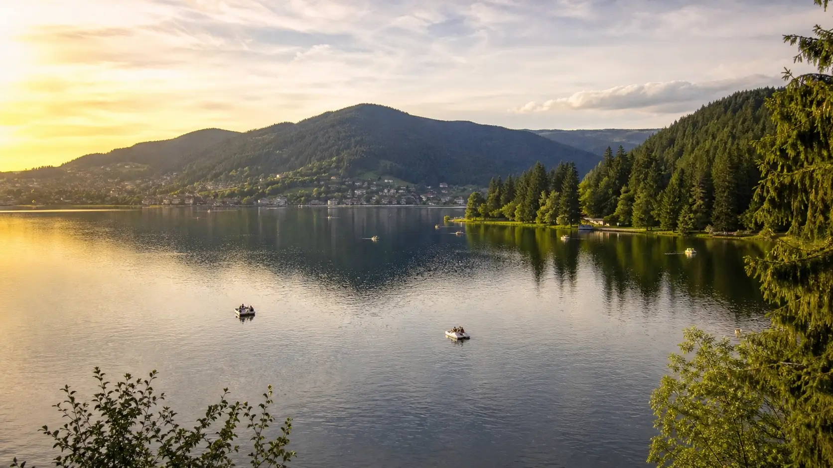 Vue du lac de Gérardmer entouré de forêts vosgiennes avec montagnes et eau calme en été