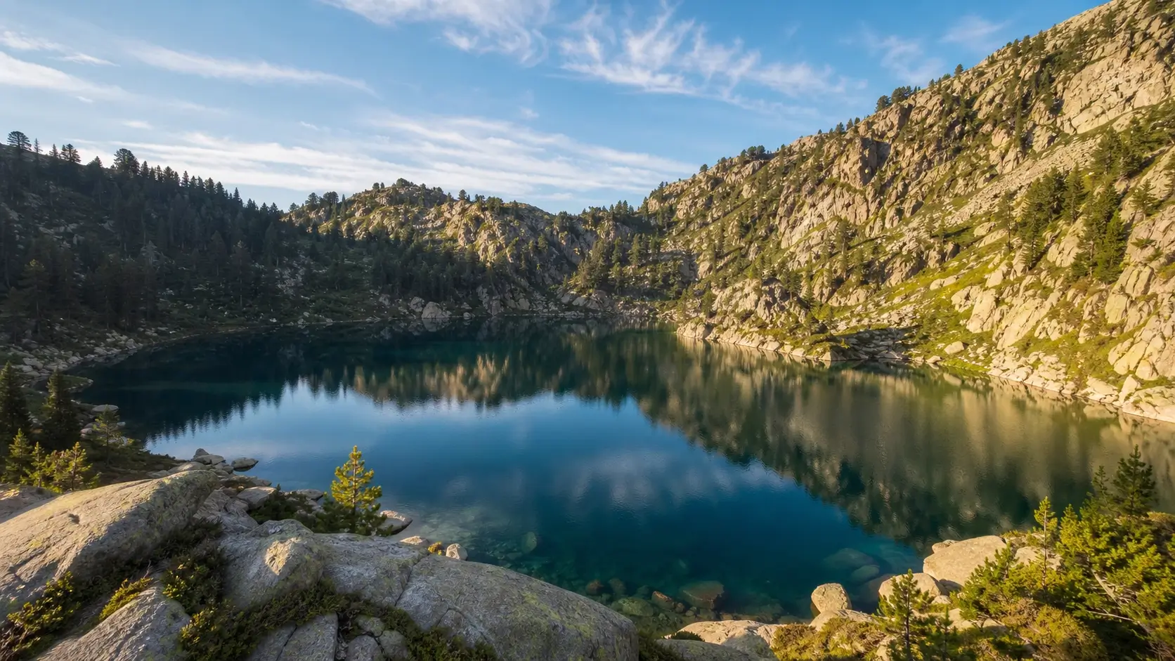 Vue du Lac Blanc dans les Vosges entouré de falaises rocheuses et de forêts, sous une lumière matinale