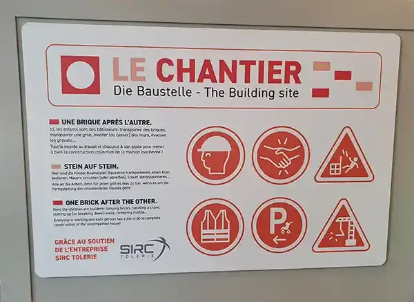 Panneau trilingue « Le chantier » présentant des consignes et des pictogrammes liés à la construction, photographié au Vaisseau à Strasbourg en 2023.