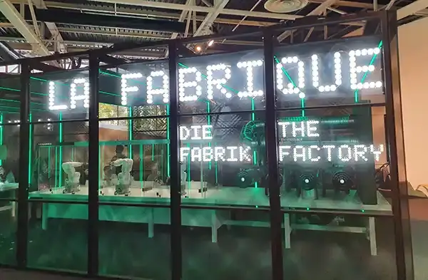 Espace « La Fabrique » du Vaisseau à Strasbourg, avec une enseigne lumineuse en français et en anglais derrière des vitrines, photographié en 2023.