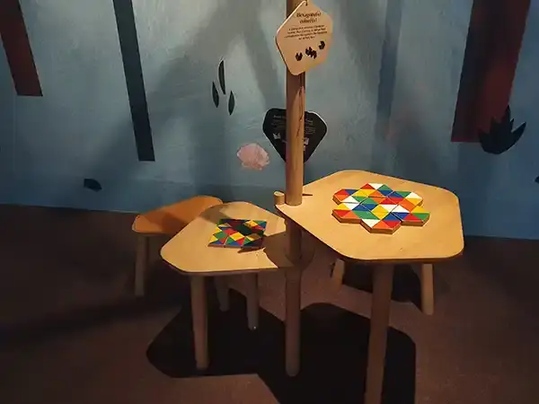 Espace ludique avec deux tables en bois proposant des jeux de mosaïques colorées, dans l’exposition « La forêt » au Vaisseau à Strasbourg, photographié en 2023.